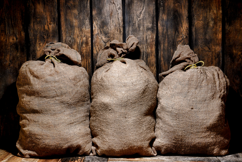 Three vintage brown burlap sac bags filled with dry goods.