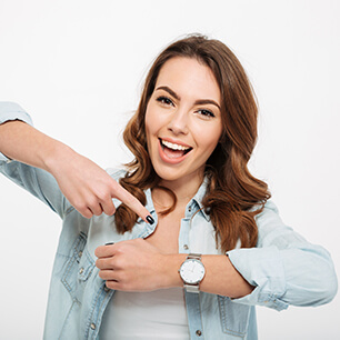 Photo of cheerful young woman pointing at her watch.