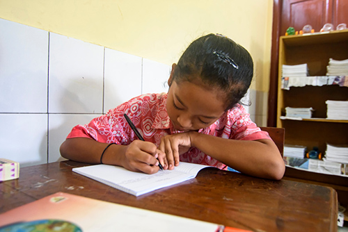 Elementary school girl writing in a notebook.