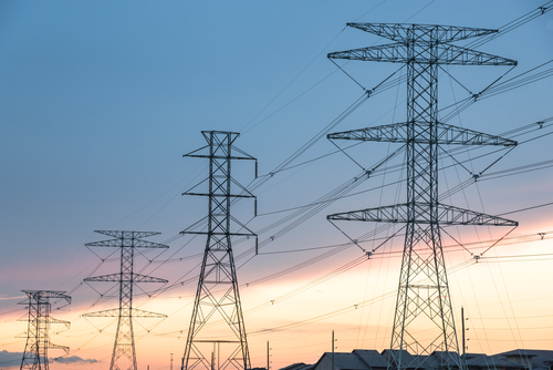 Group silhouette of transmission towers (power tower, electricity pylon, steel lattice tower) at sunset in Humble, Texas, US.