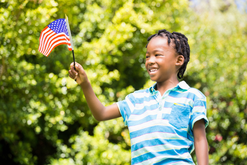 Smiling boy waving american flag in the park