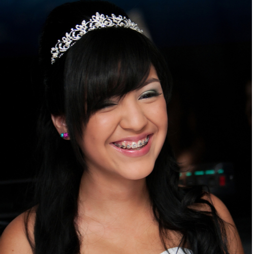 A 15 year old hispanic girl celebrates her birthday with a tiara and fancy white dress