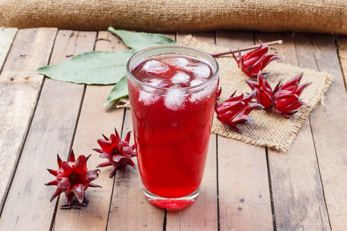 Glass of cold roselle juice - healthy food against wood.