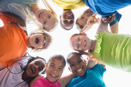 Pupils in a huddle smiling down at camera outside.