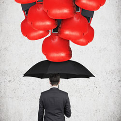 giant boxing gloves punching down toward a man in a suit holding up an open umbrella