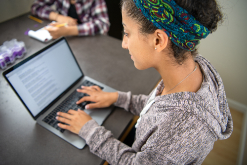 High school student girl working on a laptop computer.