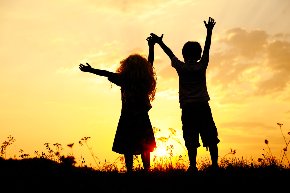 Children playing on a meadow at sunset in summer.