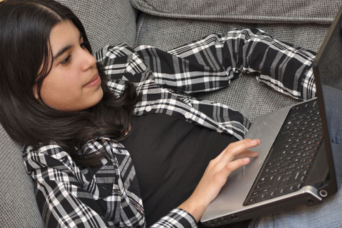 girl sitting on couch using laptop