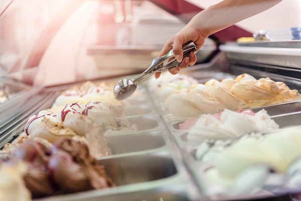 a ice cream shop freezer, someone scooping ice cream