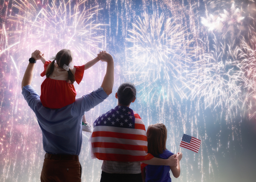Patriotic holiday. Happy family, parents and daughter child girl with American flag outdoors. USA celebrate 4th of July.