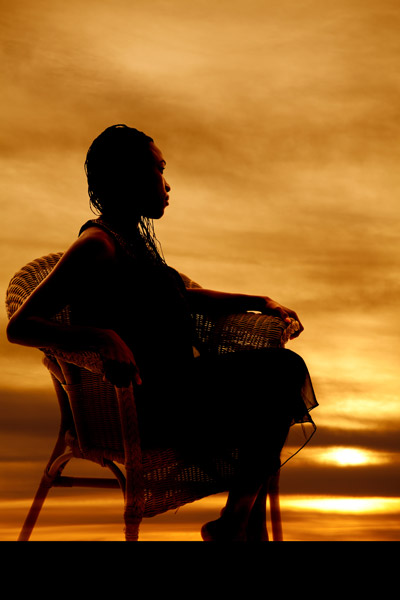silhouetted seated woman with sunset in background