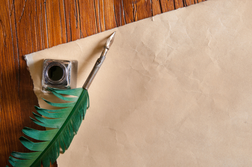 Green quil pen and black inkwell with old papers and books