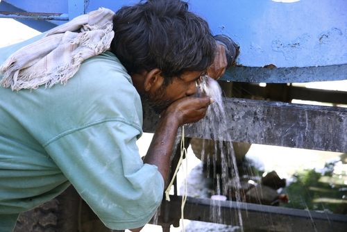 man drinking water from tank, south india