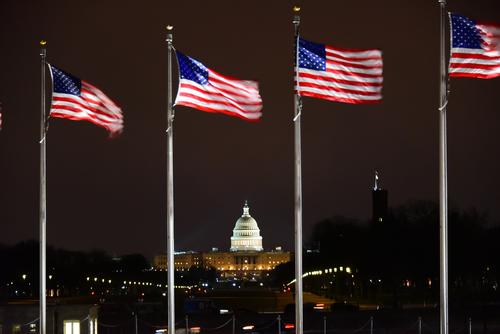 US Capitol Building with US flags flying in the wind - Washington DC, USA