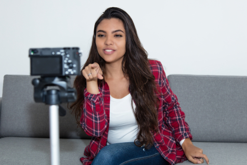 Latin american vlogger girl pointing at camera at home.