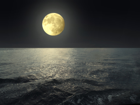 a full moon shining over the ocean