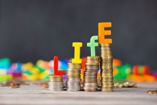 Life cost or cost of living concept with colorful letters on ascending piles of money.
