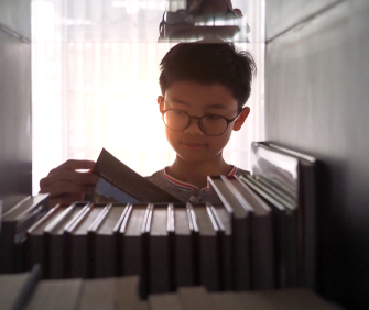 Closeup of an boy wearing a glasses reading a book at home. 