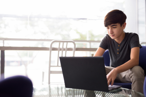 Portrait of young  teenage boy working on his computer at home.