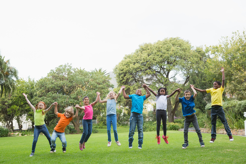 Children jumping in the park on a sunny day.