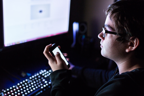 Teenager boy on computer in his room late at night.