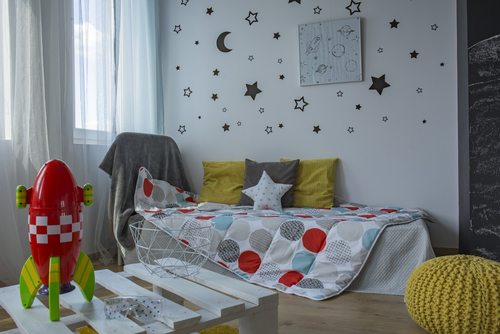A child's room with coffee table, single bed, window and blackboard wall