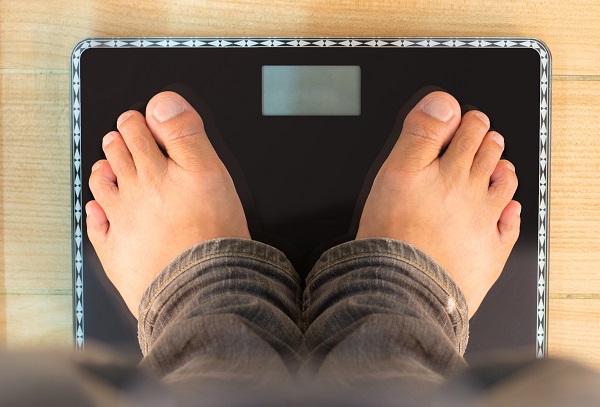 feet of man standing on bathroom scale - view from top