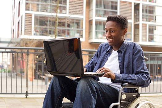 student in wheelchair using laptop