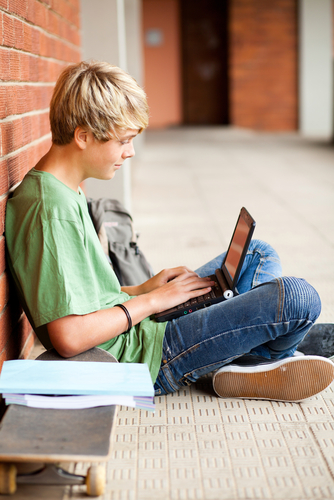 male high school student using laptop in school