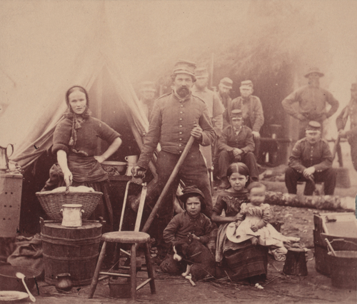The Civil War, woman with sleeves rolled up holding basket, with a soldier and three children, soldiers in the background, camp of 31st Penn Infantry near Washington DC, photograph, February, 1862.