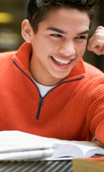 Young boy smiling at his desk with a notebook.