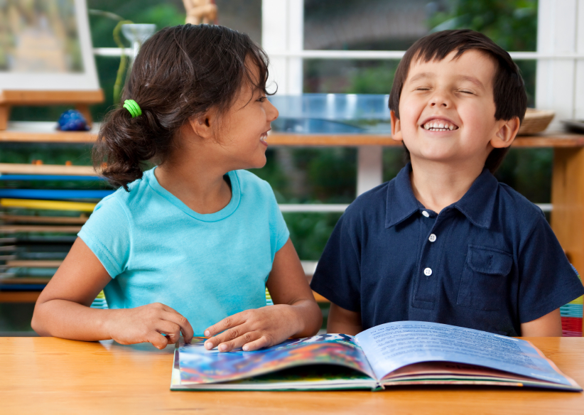 kids smiling and reading a book
