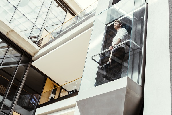 Businessman taking modern glass elevator to the upper floors