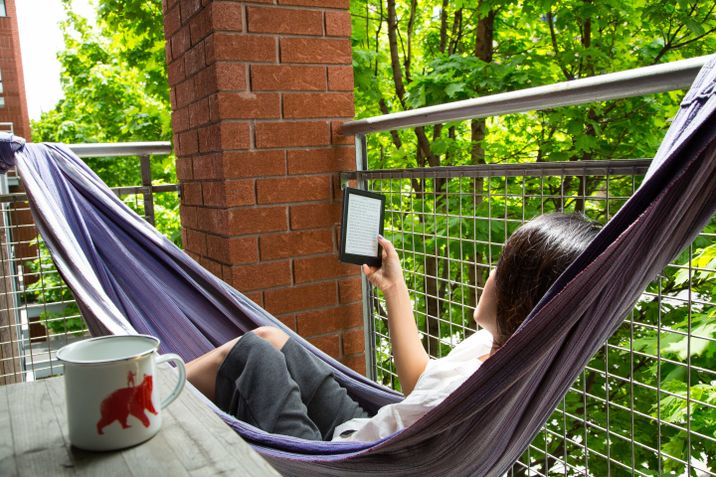 Yunjung Na reading from her Kobo eReader in a hammock on the balcony