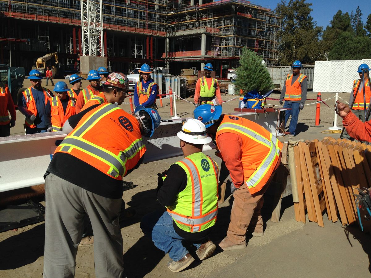 Construction workers sign the final beam before it is hoisted to the top of the Meyer and Renee Luskin Conference Center