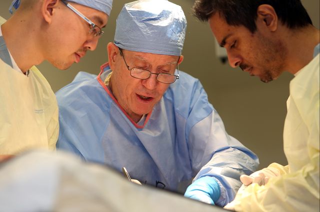 Dr. Warwick Peacock works with two surgical residents.