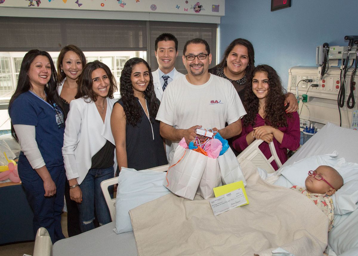 Members of "Teamwork Makes the Dream Work," medical staff and family members at the bedside of Vicky Mezquita