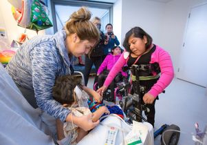 Josie Alvarez with a Mattel Children's Hospital patient. Her twin sister, Teresita, in a wheelchair, looks on.
