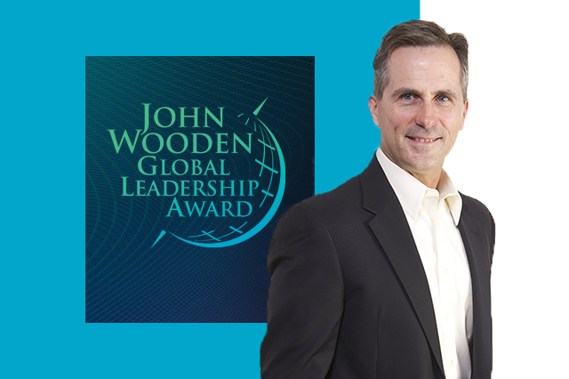 Doug Larratt stands next to sign for Wooden Global Leadership Award
