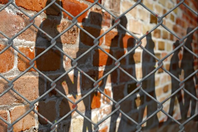 Image of youths behind chain-link fence