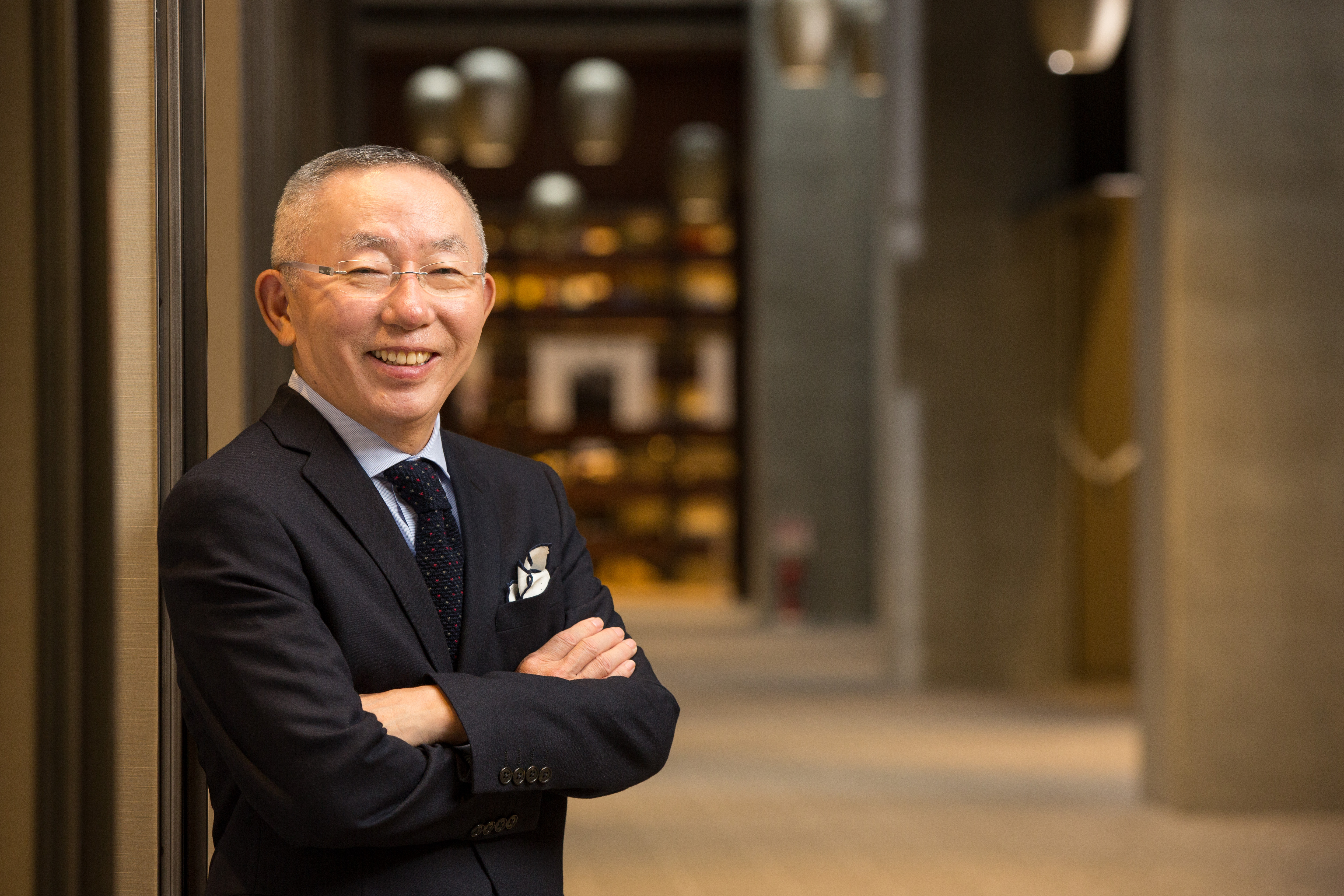 Tadashi Yanai in a suit stands with his arms crossed