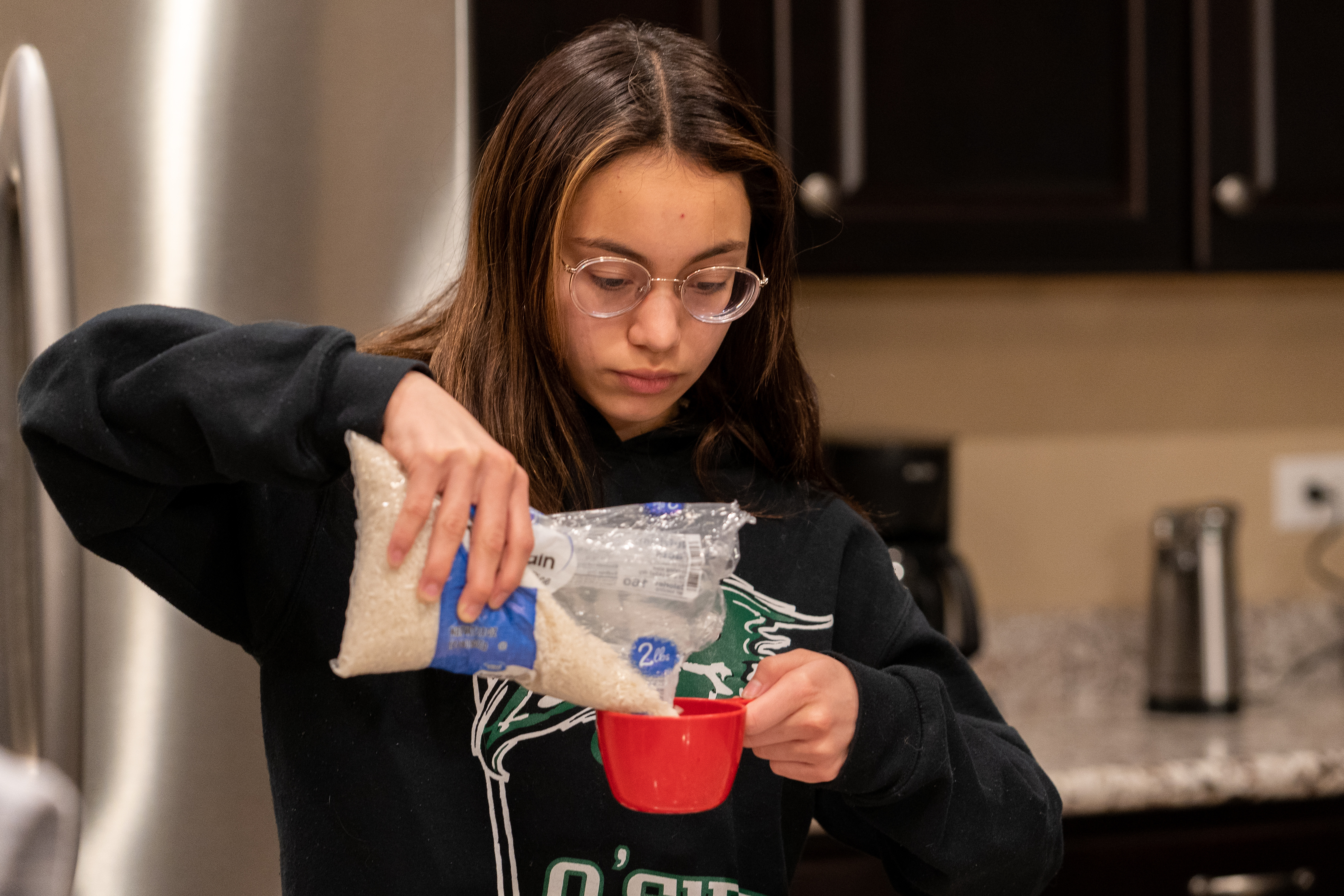 Teenage girl measuring rice