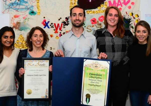 Members of legal clinic holding commendations