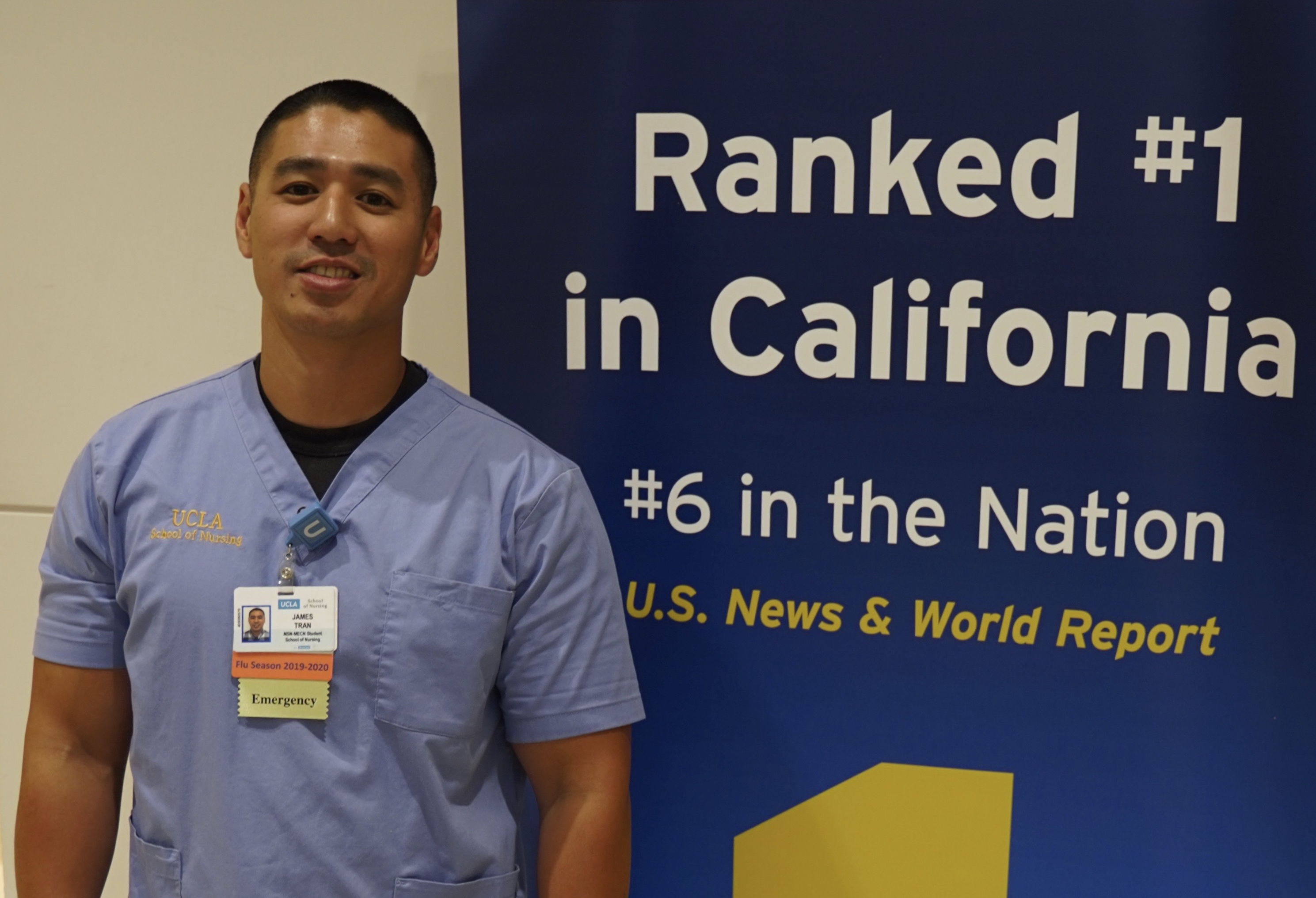 James Tran in scrubs nest to UCLA No. 1 sign
