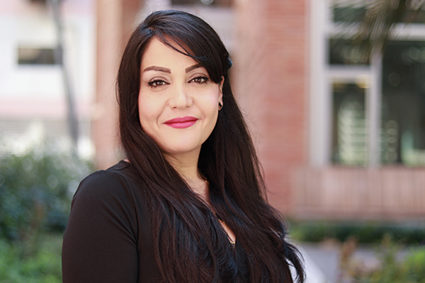 Head-and-shoulders photo of Nasim Annabi wearing black blazer in front of a brick building.