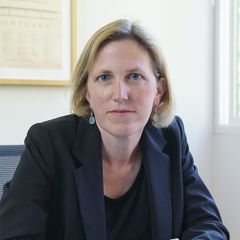 A portrait of Kimberly Clausing seated, wearing a dark blazer.