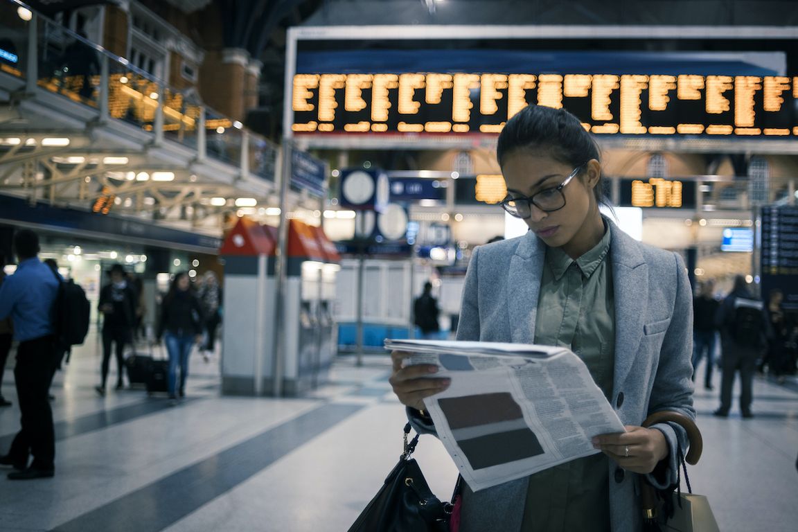 Woman reading newspaper in train station