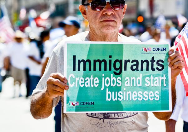 Man with immigrants create jobs sign