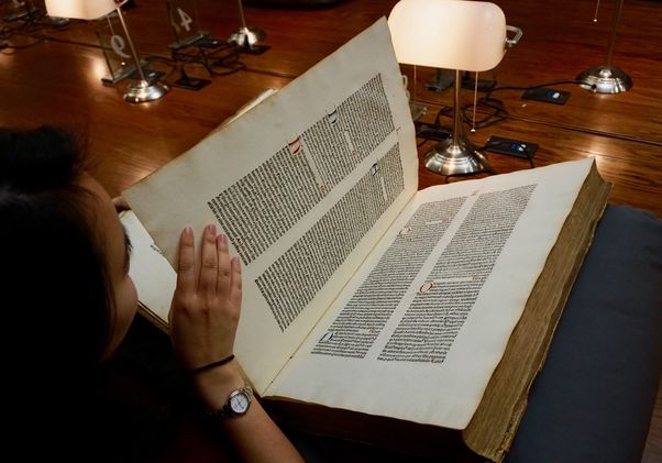 Click to open the large image: Student reading old book in special collections reading room