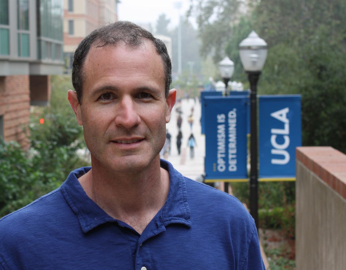 Professor Alan Castel on campus, with Bruin banners in background